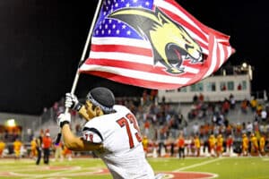 Football player waving American flag with cougar symbol