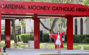 Teen graduate in front of Cardinal Mooney Catholic High school