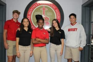 Teens in front of Mooney Catholic High school logo