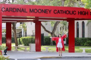 Teen graduate in front of Cardinal Mooney Catholic High school